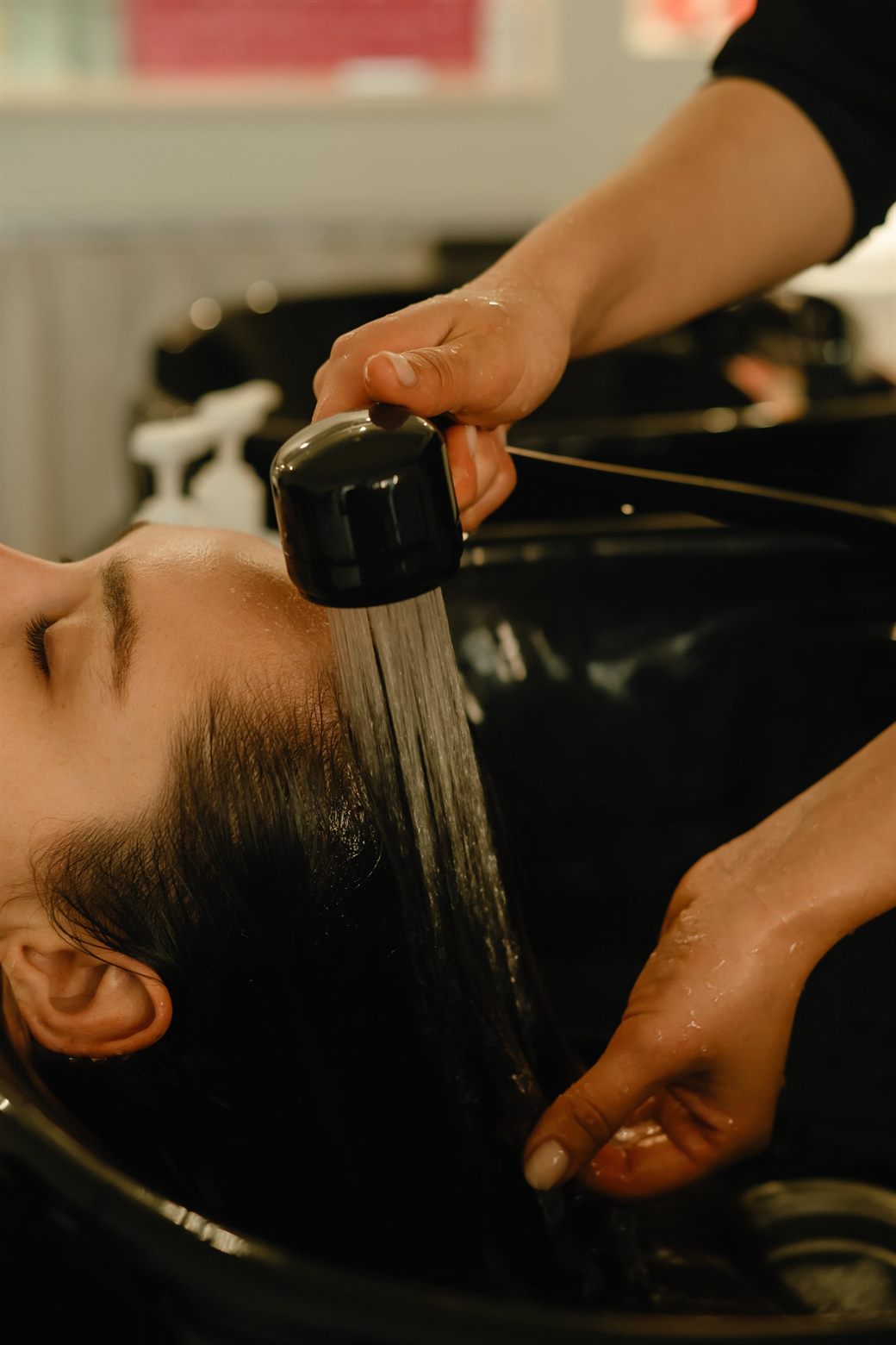 A client’s hair being gently rinsed and cared for at the wash basin.
